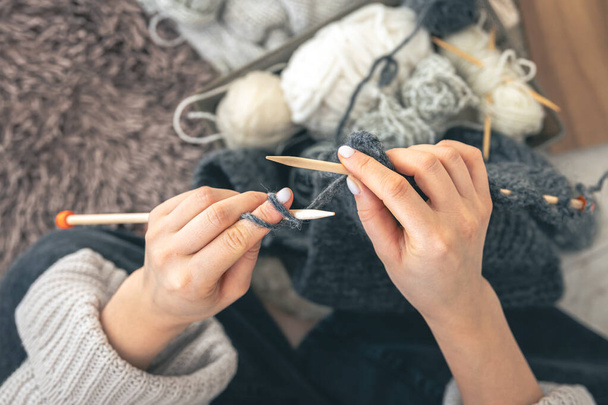 Gros plan des mains féminines tricotant un pull en laine grise. Tricot femme en fil épais. Des vêtements faits main. La fille entre pour ses passe-temps. - Photo, image