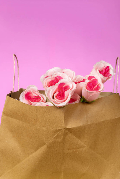 Ramo de rosas rosadas en bolsa de papel sobre fondo rosa. Día de San Valentín - Foto, Imagen