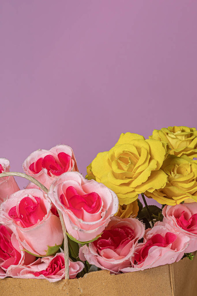 Bouquet di rose in un sacchetto di carta su sfondo rosa con spazio per la copia - Foto, immagini