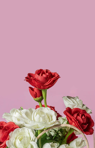 Ένα μπουκέτο κόκκινα και λευκά τριαντάφυλλα σε μια χάρτινη σακούλα με χώρο αντιγραφής για το κείμενό σας σε ροζ φόντο. - Φωτογραφία, εικόνα