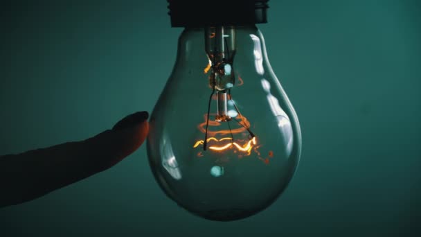 Light bulb turns on and goes out at the touch of a persons hand in the dark. Slow turning on and off of a tungsten light bulb. Filament of a blinking vintage light bulb. Energy, electricity, light - Footage, Video