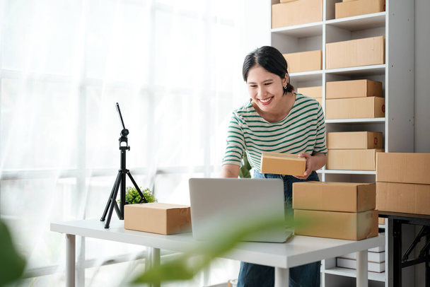 Startup small business entrepreneur or freelance Asian woman using a laptop with box, Young success Asian woman with her hand lift up, online marketing packaging box and delivery, SME concept. High - Photo, Image