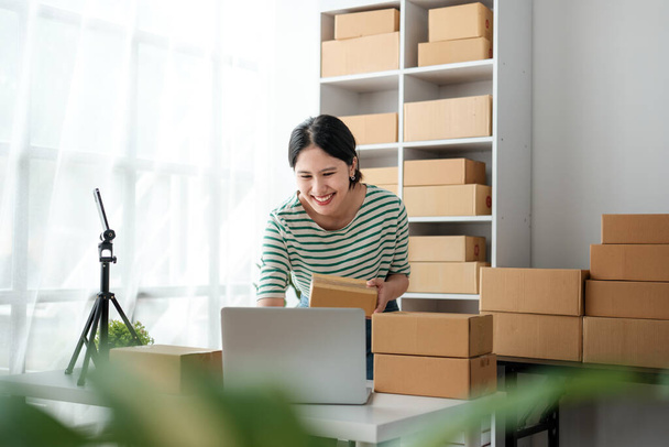 Startup small business entrepreneur or freelance Asian woman using a laptop with box, Young success Asian woman with her hand lift up, online marketing packaging box and delivery, SME concept. High - Photo, Image