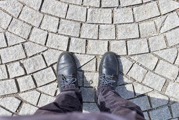 vista aérea das pernas de um homem em pé em uma calçada feita de pedras de pavimentação de granito - Foto, Imagem