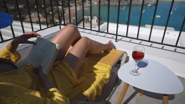 Mulher lê um livro em uma varanda com vista para o mar. - Filmagem, Vídeo
