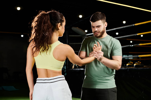 Un entrenador masculino enseña técnicas de autodefensa a una mujer en un gimnasio. - Foto, Imagen