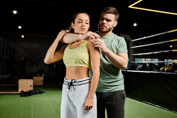 Ein männlicher Trainer demonstriert einer Frau im Fitnessstudio Selbstverteidigungstechniken. - Foto, Bild