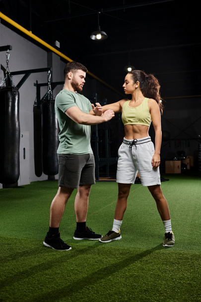 Un entrenador masculino enseña técnicas de autodefensa a una mujer en un gimnasio. - Foto, Imagen