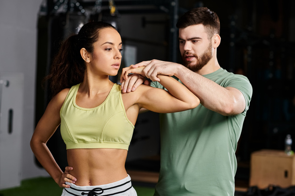 Un entrenador masculino enseña técnicas de autodefensa a una mujer en un gimnasio, centrándose en el empoderamiento y la unidad. - Foto, Imagen