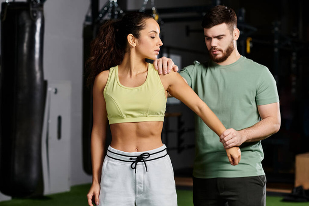 Ein männlicher Trainer demonstriert einer Frau in einem Fitnessstudio Selbstverteidigungstechniken und zeigt Einheit und Stärkung durch Fitness. - Foto, Bild