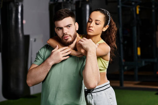 Un entraîneur masculin démontre des techniques d'auto-défense à une femme dans un cadre de gymnastique, montrant son soutien et son autonomisation. - Photo, image