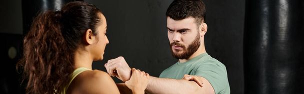 Un entrenador masculino demostrando técnicas de autodefensa a una mujer en un gimnasio. - Foto, Imagen