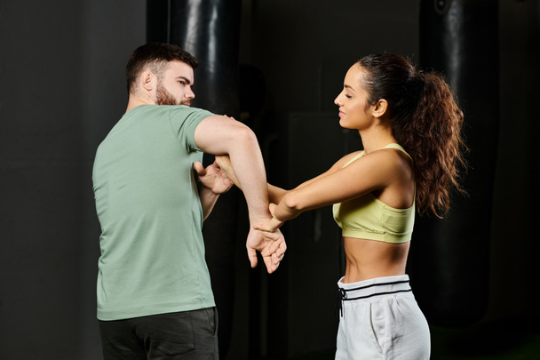 Ein männlicher Trainer bringt einer Frau in einem Fitnessstudio Selbstverteidigungstechniken bei und demonstriert Stärke, Unterstützung und Einheit. - Foto, Bild