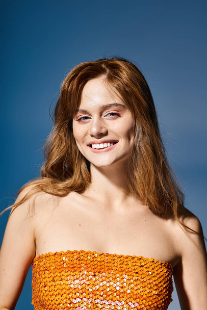 Beauty portrait of smiling woman with blue eyes, peach makeup and freckles on blue background - Foto, Imagen