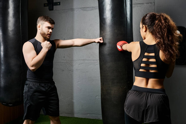 Тренер-мужчина направляет брюнетку-спортсменку в активной одежде во время строгой тренировки на боксёрском ринге. - Фото, изображение