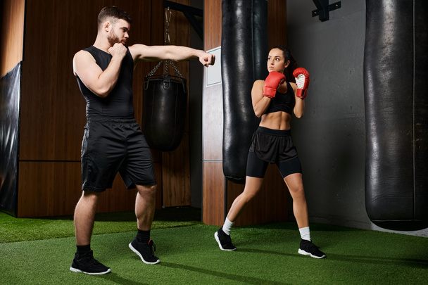 A male trainer guides a brunette sportswoman in active wear as they spar in a boxing ring in a gym. - Photo, Image