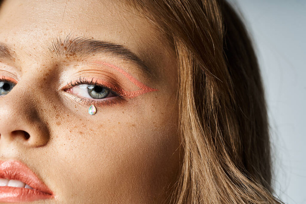 Closeup retrato de beleza de olhos de mulher com delineador de maquiagem de pêssego, jóias rosto lacrimogêneo e sardas - Foto, Imagem