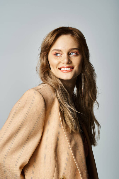 Smiling woman in beige jacket, wearing nude makeup with face jewels, looking away - Foto, immagini