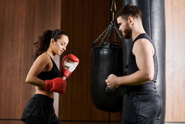 Ein männlicher Trainer in der Nähe einer brünetten Sportlerin im aktiven Boxsport in einem Fitnessstudio. - Foto, Bild