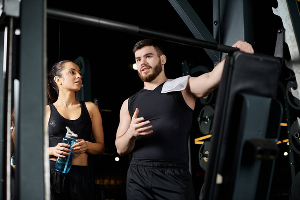 Mężczyzna trener osobisty i brunetka sportowiec stojący razem w siłowni. - Zdjęcie, obraz
