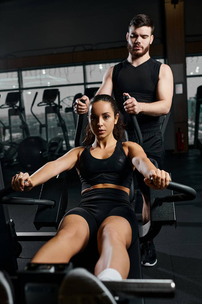 Mužský trenér vede soustředěnou brunetku sportovkyni v tělocvičně cvičení, tlačí jeden druhého k dosažení jejich fitness cílů. - Fotografie, Obrázek