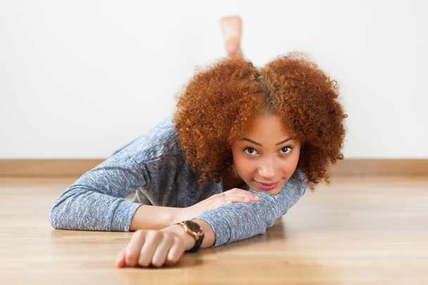 Afrikkalainen amerikkalainen teini tyttö makaa lattialla
 - Valokuva, kuva