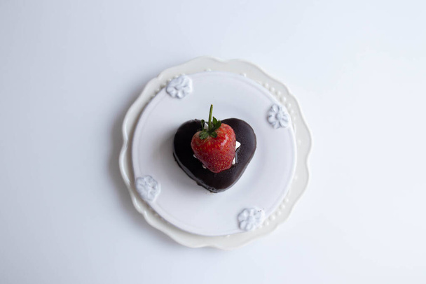 Ciasto czekoladowe z białym bitą śmietaną i czerwonym sercem na białym tle - Zdjęcie, obraz