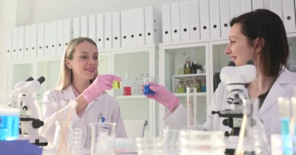 Tubos de ensaio com líquido multicolorido ou álcool em frascos em laboratório. Cientistas clink óculos no laboratório - Filmagem, Vídeo