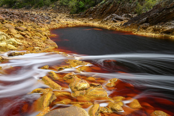 Foaming water rushes over the colorful, iron-laden rocks in the Rio Tinto river - Foto, Imagen