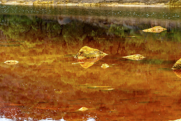 Capas impactantes de tierra y una veta vívida de agua roja alinean el suelo agrietado del Río Tinto - Foto, Imagen
