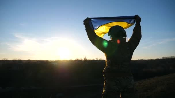 Soldat féminin en uniforme et casque levé drapeau sur la colline. Médecin militaire ukrainien tenant le drapeau de l'Ukraine. Victoire contre l'agression russe. Concept de résistance à l'invasion. Moteur lent. - Séquence, vidéo