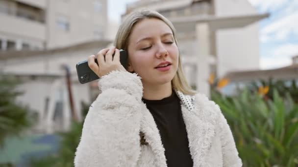 Blonde Frau nutzt Smartphone im Freien in lässiger Kleidung - Filmmaterial, Video