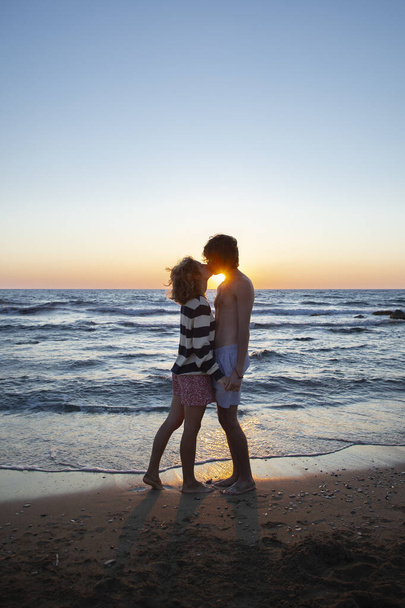 silhouettes d'un jeune couple embrassant sur fond de mer et de coucher de soleil, un mec et une fille amoureux ensemble en vacances. profiter du moment, sentiments tendres, passe-temps agréable. Saint Valentin - Photo, image