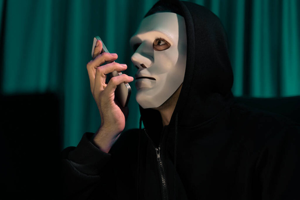 Weiße kriminelle anonyme Maske, die den IT-Besitzer auffordert, Lösegeld mit einer großen Datenbank zu bedrohen, die Verschlüsselung von Passwörtern durch Programmierung von Hacks installiert und versucht, die Privatsphäre unsicher zu machen. Pekuniär. - Foto, Bild