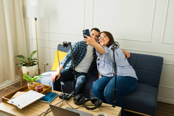 Latynoska kobieta robi sobie selfie ze swoim szczęśliwym gościem po wspólnym nagraniu odcinka podcastu  - Zdjęcie, obraz