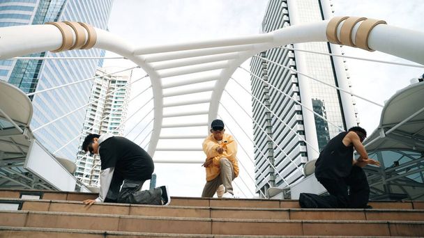 Egy csapat boldog break táncos sétál le a lépcsőn, miközben együtt táncolnak a városban. A profi hipster energikus léptekkel néz a kamerába. Alacsony szögű kamera. Kültéri sport 2024. Élénk.. - Fotó, kép