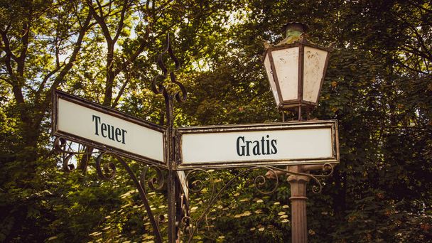 An image with a signpost pointing in two different directions in German. One direction points to Free, the other points to Expensive. - Photo, Image