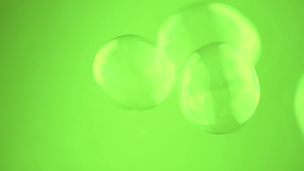 Gruppo piccole bolle di sapone galleggiare su uno sfondo verde nello spazio vuoto. Chiudete. Sfere d'acqua cangianti trasparenti soffianti. Abstract. Moto offuscata, concentrati. Isolato. Chiave cromatica. Rallentatore. - Filmati, video