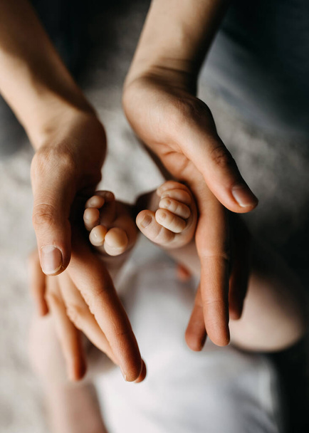 Les mains de la mère tenant les pieds d'un nouveau-né, symbolisant l'amour et les soins. - Photo, image