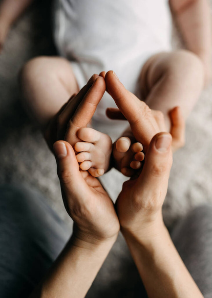 Ręce matki trzymające stopy noworodka, symbolizujące miłość i troskę. - Zdjęcie, obraz