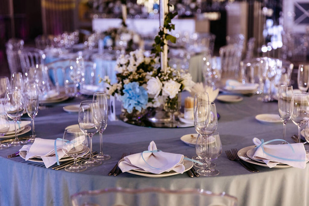 Een elegant gedekte trouwreceptietafel in blauwe tinten met borden, glazen en textielzakdoeken. - Foto, afbeelding