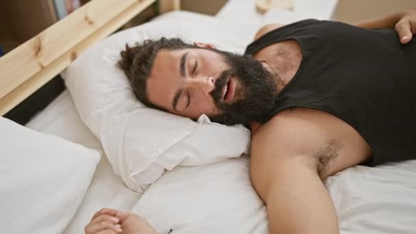 Een ontspannen Spaanse man met een baard die in een slaapkamer slaapt en rust en comfort uitstraalt.. - Video