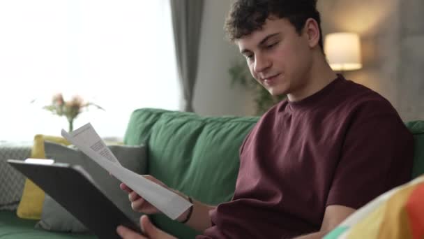 jeden młody człowiek biały nastolatek student nauka czytania podczas siedzieć w domu przygotować egzamin lub pracować nad projektem prawdziwych ludzi edukacja koncepcja slow motion - Materiał filmowy, wideo