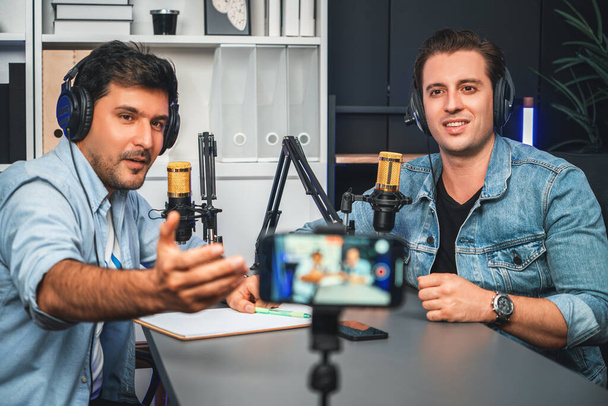 Host channel of creative broadcaster living by smartphone in positive podcast with special guest in list script to advice listeners, wearing headsets, using mic radio record at studio. Sellable. - Photo, Image