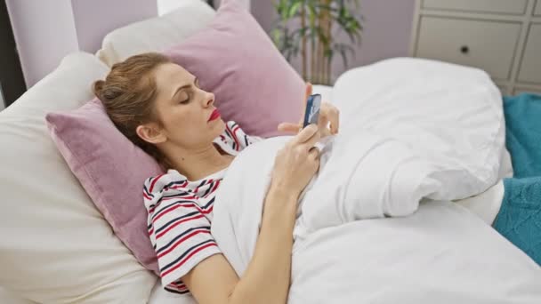 Spaanse vrouw ontspannen met de telefoon in de slaapkamer, portretteren verbonden levensstijl thuis - Video