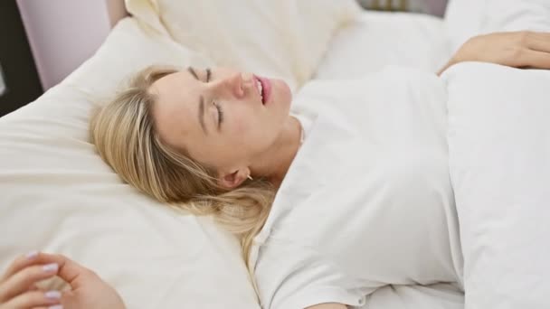 Μια γαλήνια καυκάσια γυναίκα αναπαύεται στο κρεβάτι, που απεικονίζει χαλάρωση και άνεση μέσα σε ένα σπιτικό περιβάλλον. - Πλάνα, βίντεο