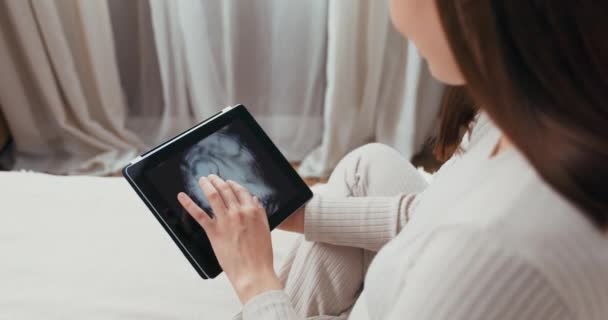 Rögzítése a pillanat koncepció terhes nő csinál egy közeli kép a hasát, míg a kórházban, és csodálja azt a táblagépen. - Felvétel, videó