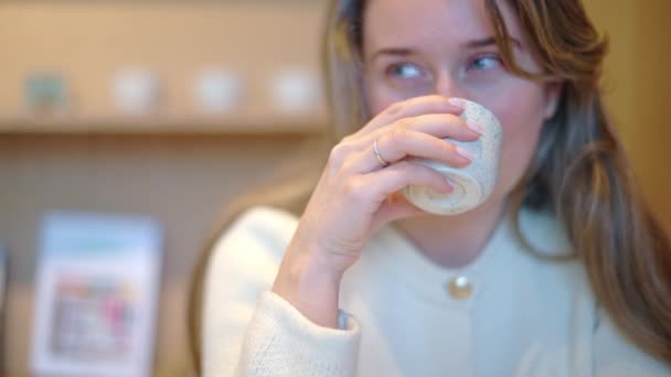 vrouw drinken latte kunst koffie uit keramische beker in een cafe - Video