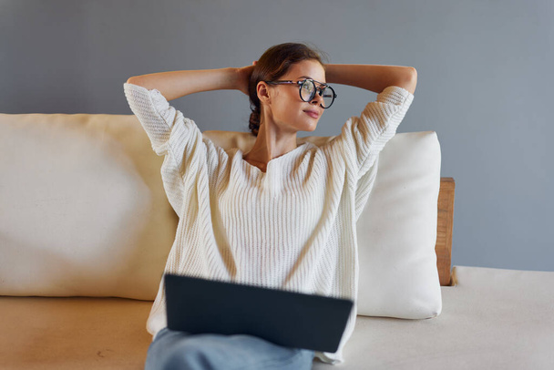 Mosolygó nő használja laptop a kanapén a modern otthoni irodában Ő egy szabadúszó dolgozik neki startup, élvezi a kényelmet és kényelmet a munka otthonról A szoba tele van természetes - Fotó, kép