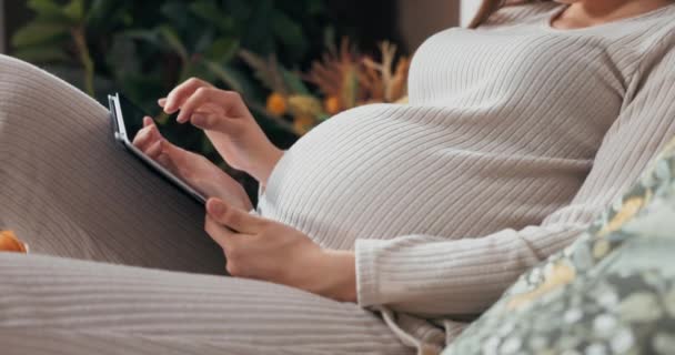 Lähikuva laukaus raskaana olevat naiset kädet pitämällä tabletti, pyyhkäisemällä ja selaamalla kuvia harkittuja ilme. - Materiaali, video
